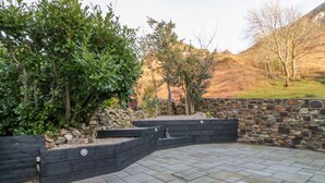 A landscaped outdoor area with stone walls, a seating bench, and a variety of plants. - Bwthyn Carregwen (Penmaenmawr)