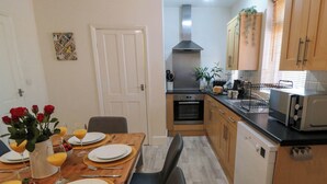 A compact kitchen with wooden cabinets, a microwave, and a stove. - The Tannery (Whitby)