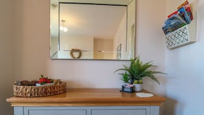 A wooden vanity with a mirror above it, a basket with strawberries, a small potted plant, and a magazine rack on the wall. - The Tannery (Whitby)