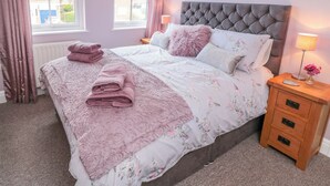 A bedroom with a bed, a nightstand, a window, and a radiator. - The Tannery (Whitby)