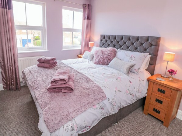 Een slaapkamer met een bed, nachtkastje, raam en radiator.