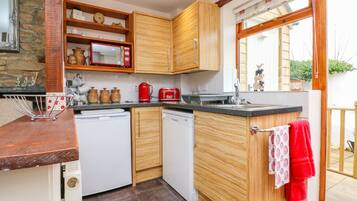 Una cocina compacta con armarios de madera, microondas, tostadora y lavavajillas.