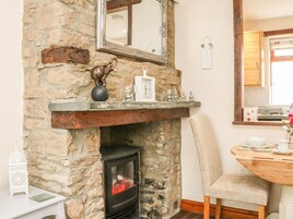 Una chimenea de piedra con repisa, un espejo encima y una mesa con una silla a un lado.