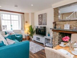 Una sala de estar con sofá, televisor, chimenea y comedor con mesa y sillas.