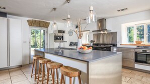 Una cocina moderna con una isla central, electrodomésticos de acero inoxidable y taburetes de madera.