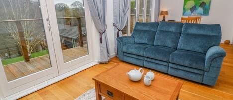 A living room with a blue sofa, wooden coffee table, and a sliding glass door leading to a balcony.