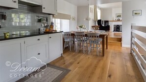 Una cucina moderna con mobili bianchi, un piano di lavoro nero e un'area pranzo con sedie e tavolo in legno.