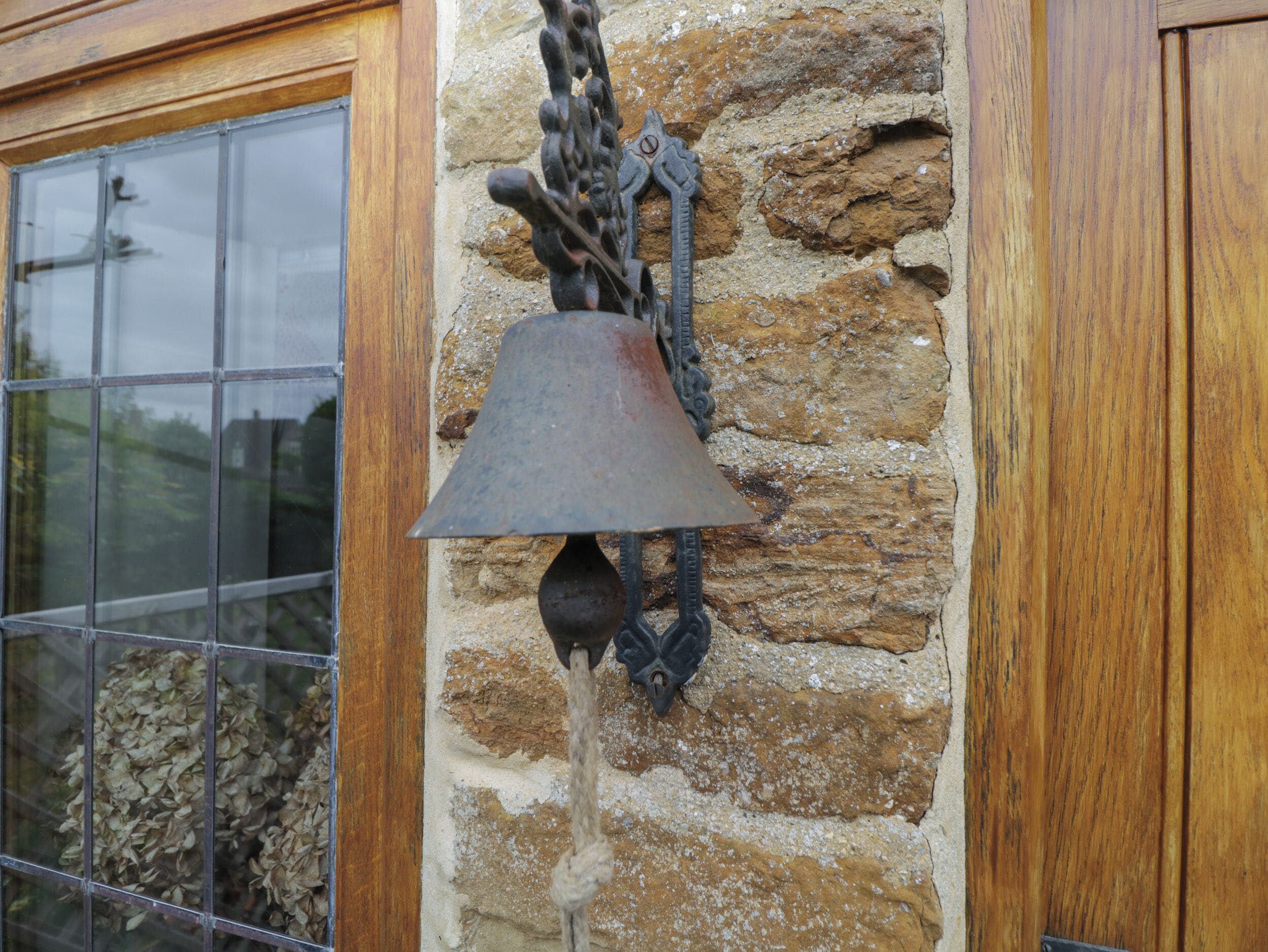 Una pared de piedra con una campana de metal colgada.