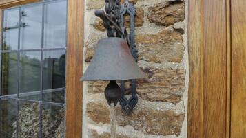 Una pared de piedra con una campana de metal colgada.