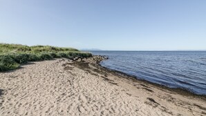 En sandstrand med klar himmel och stilla hav.