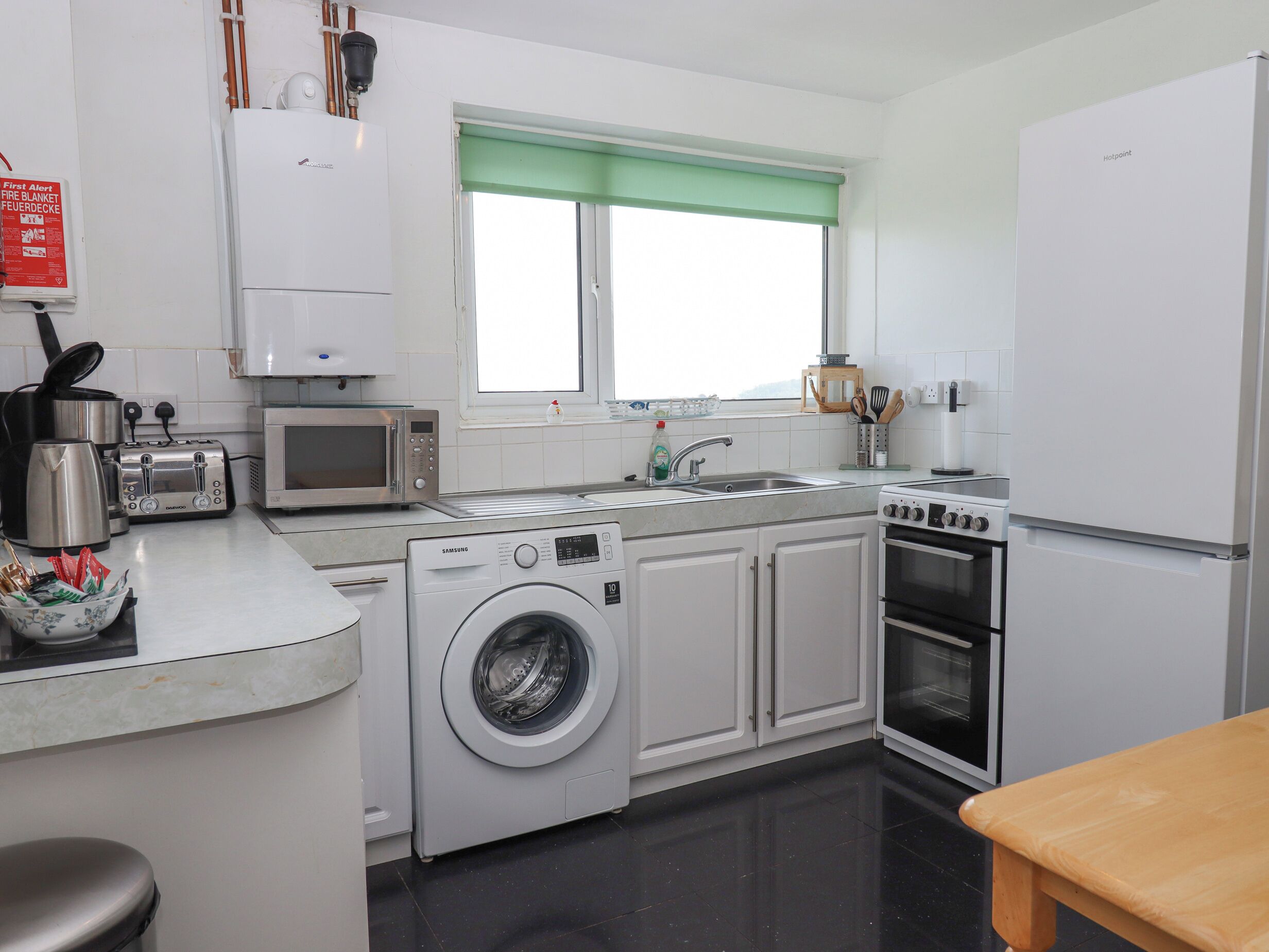 A compact kitchen with a washing machine, microwave, toaster, sink, and oven.