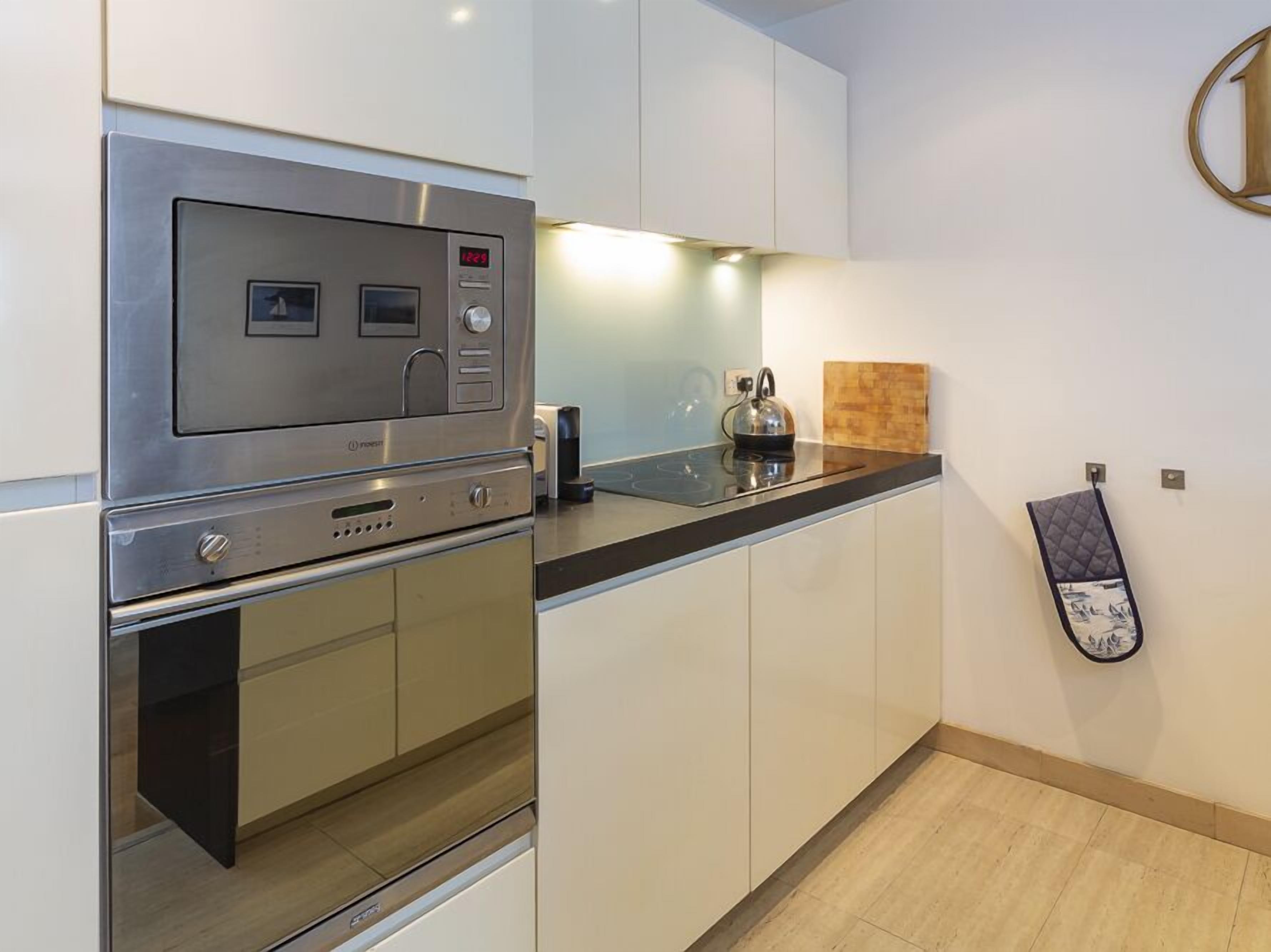 Een moderne keuken met roestvrijstalen apparatuur, een zwart aanrecht en witte kastjes.