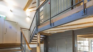 A multi-level interior with a wooden staircase, a mezzanine, and a garage door.