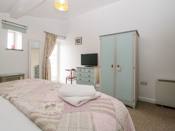 A bedroom with a bed, a dresser, a television, and a wardrobe.