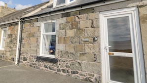 A stone building with a gabled roof, a dormer window, and a door with a glass panel.