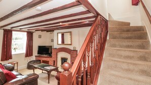 A living room with a fireplace, a television, and a staircase. - Dove Cottage (Whitby)