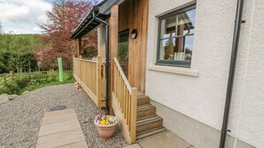 A building with a wooden deck, a small set of stairs leading to a door, and a window. - Fois House (Callander)