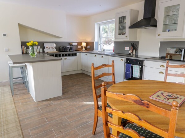A modern kitchen with white cabinets, a wooden dining table, and a built-in island.