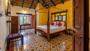 A four-poster bed with a wooden frame, a small table with a patterned tablecloth, and a chair. - amã Stays & Trails, Rare Earth Estate - Coorg (Madikeri)