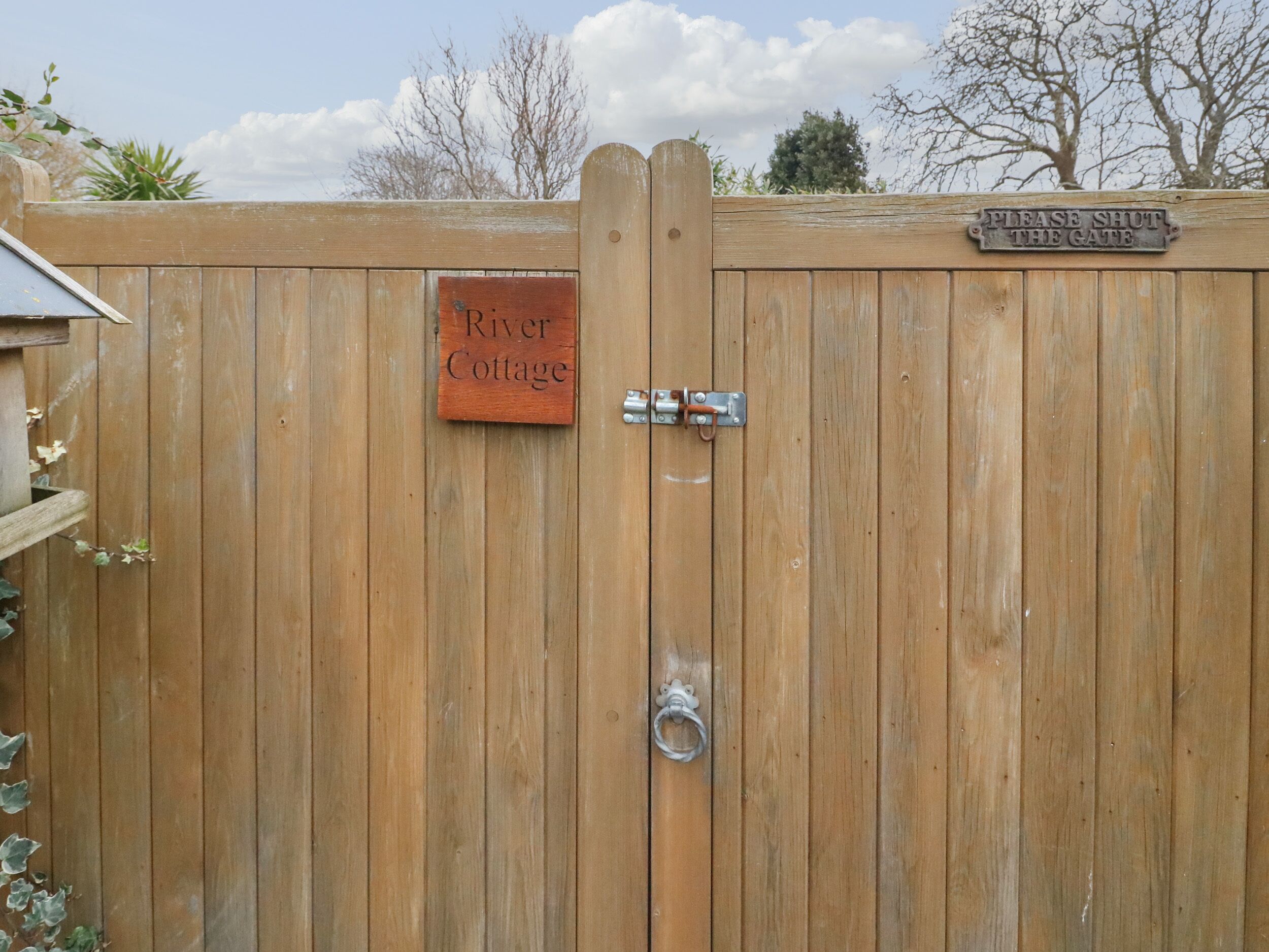 A wooden gate with a sign that reads "River Cottage."