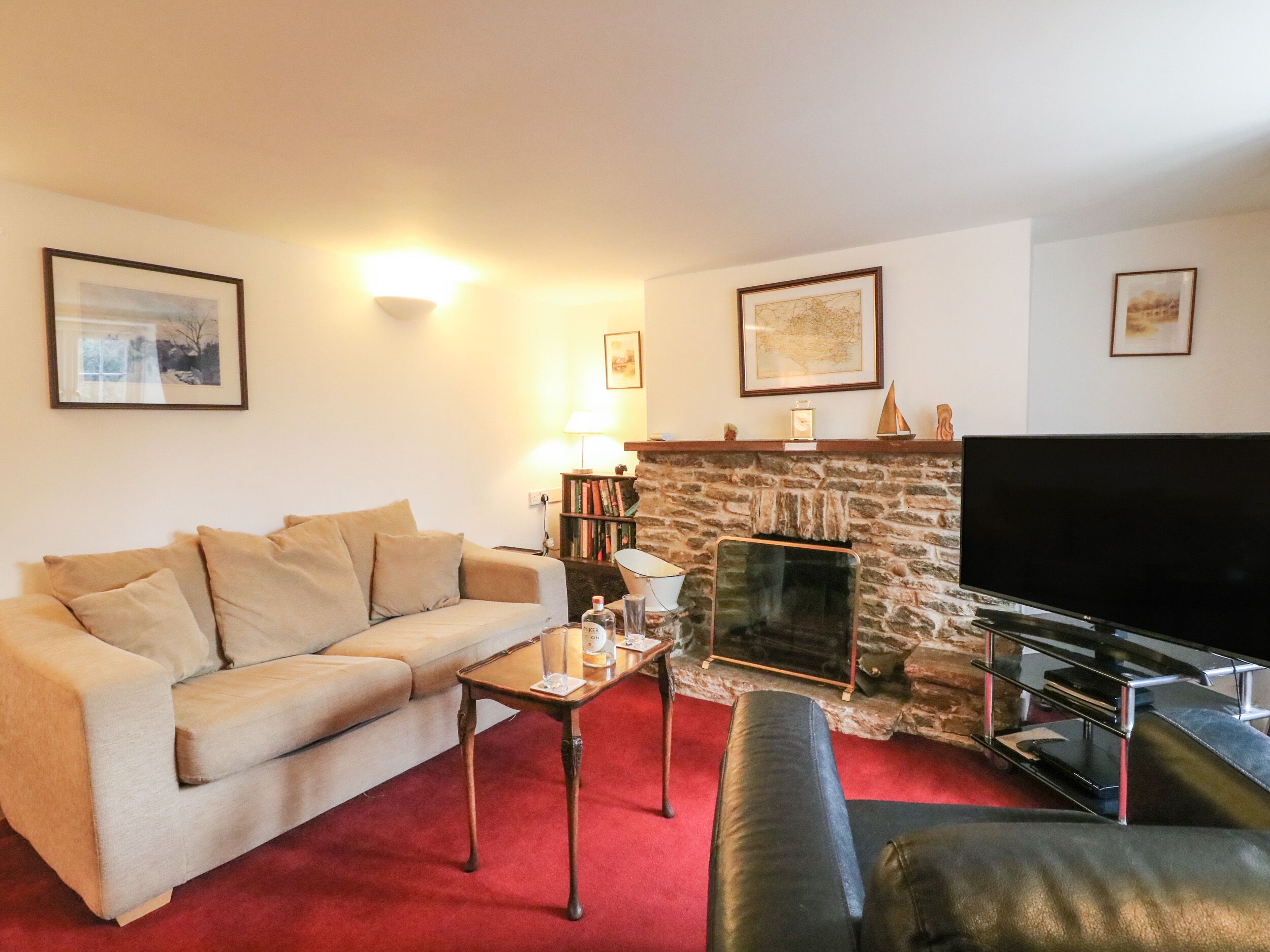 A living room with a sofa, a coffee table, a fireplace, a TV, and framed pictures on the wall.