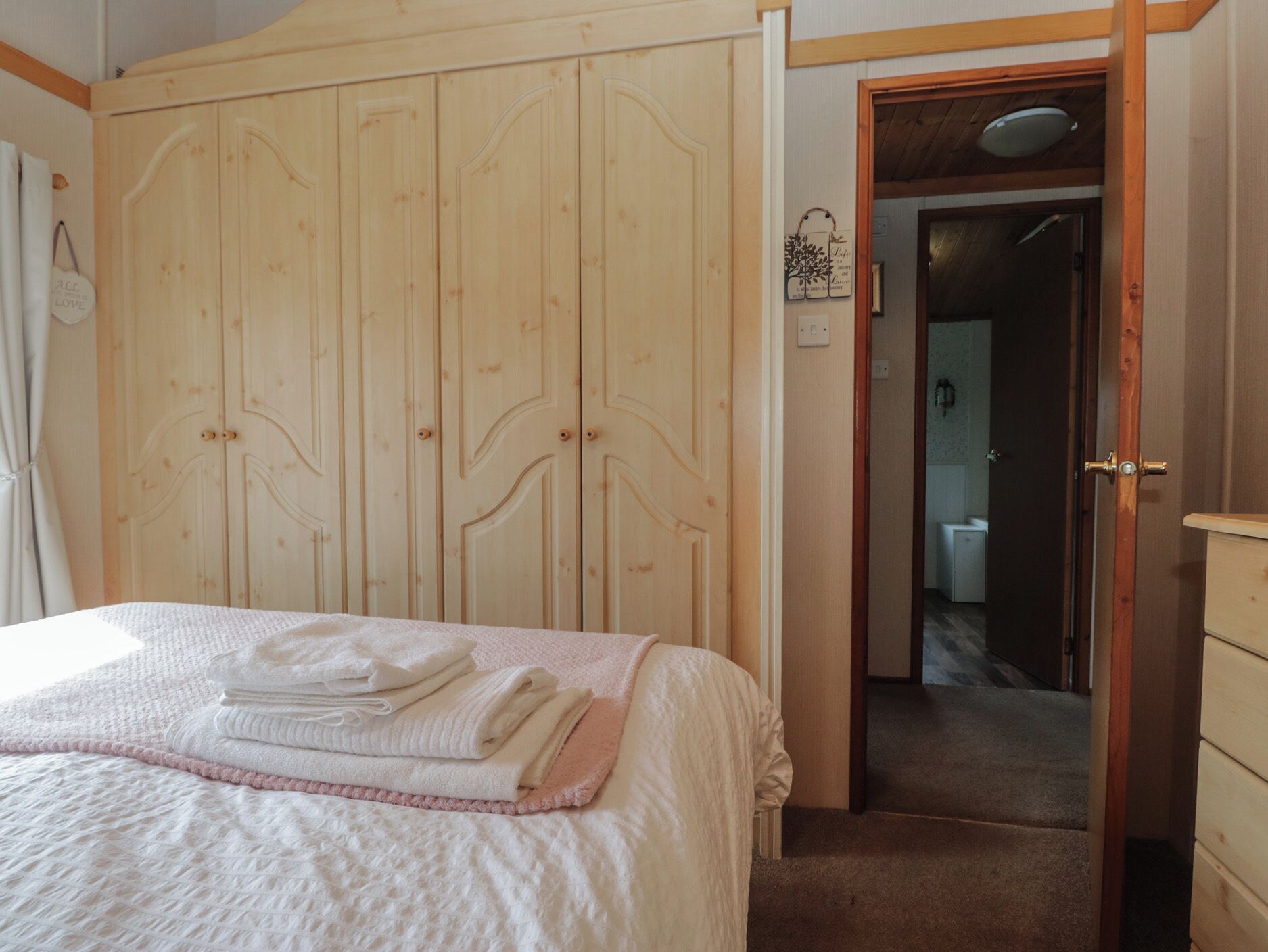 Un dormitorio con cama, armario de madera y puerta que da al baño.