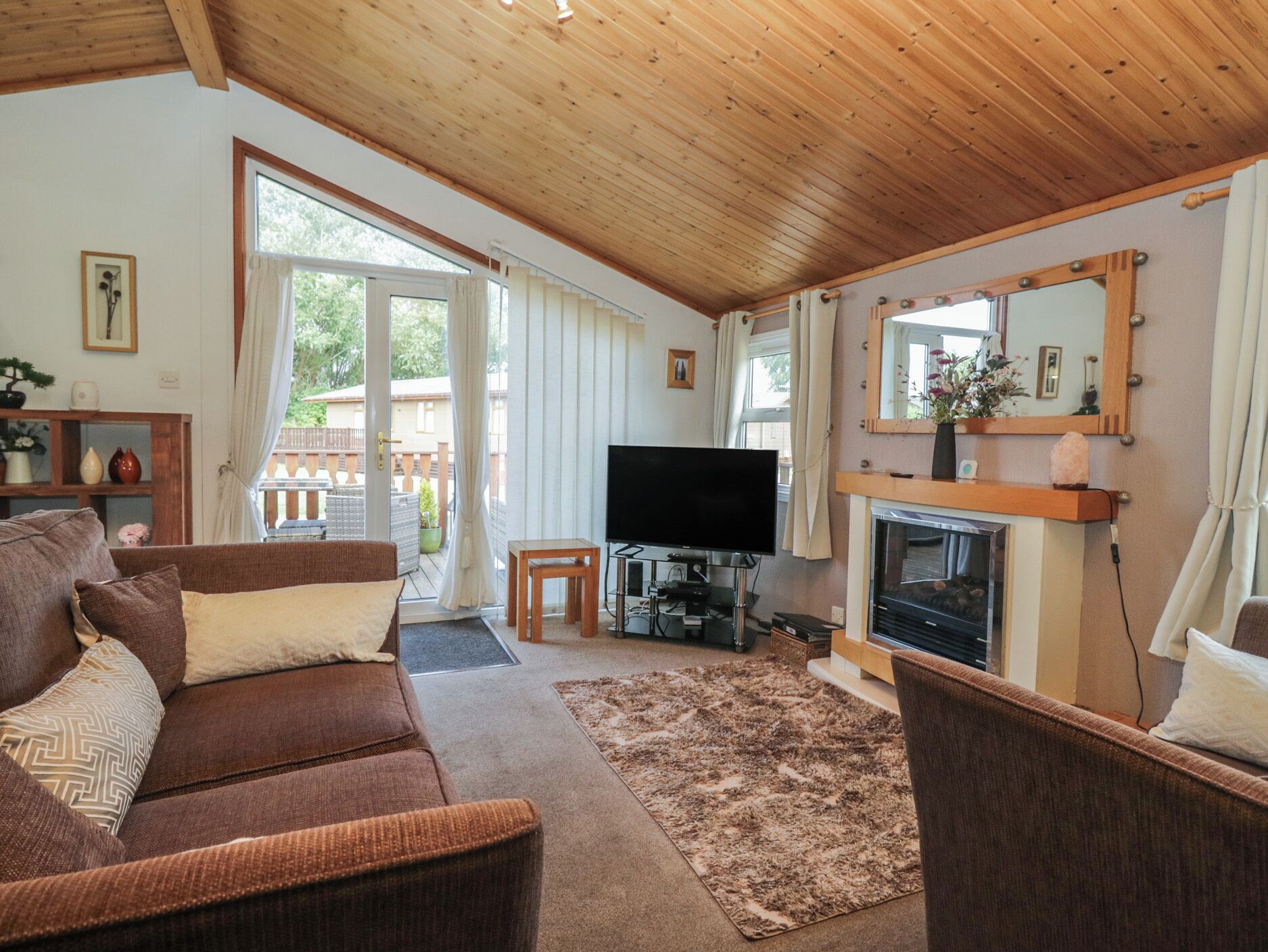 Una sala de estar amoblada con sofá, televisión, chimenea y vistas al exterior.