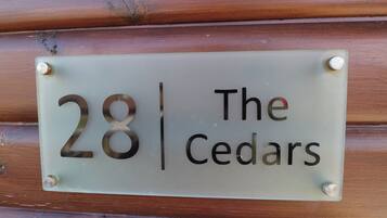 A house number sign with the number 28 and the name 'The Cedars' on a wooden wall.
