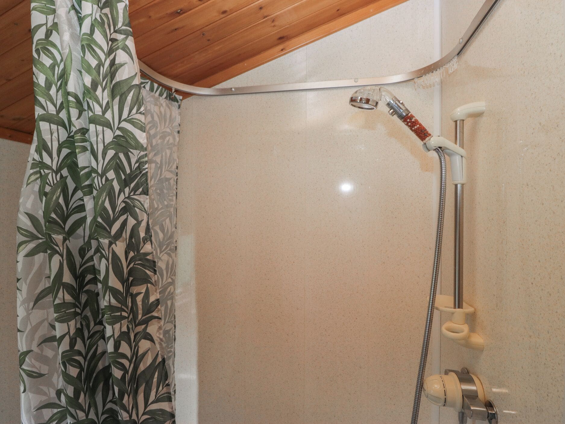 A shower with a handheld showerhead and a wall-mounted faucet.