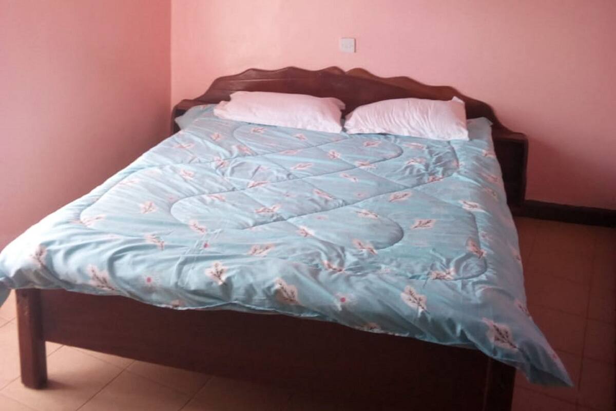Ein Schlafzimmer mit einem Bett, einem Holz-Kopfteil und einer rosafarbenen Wand.