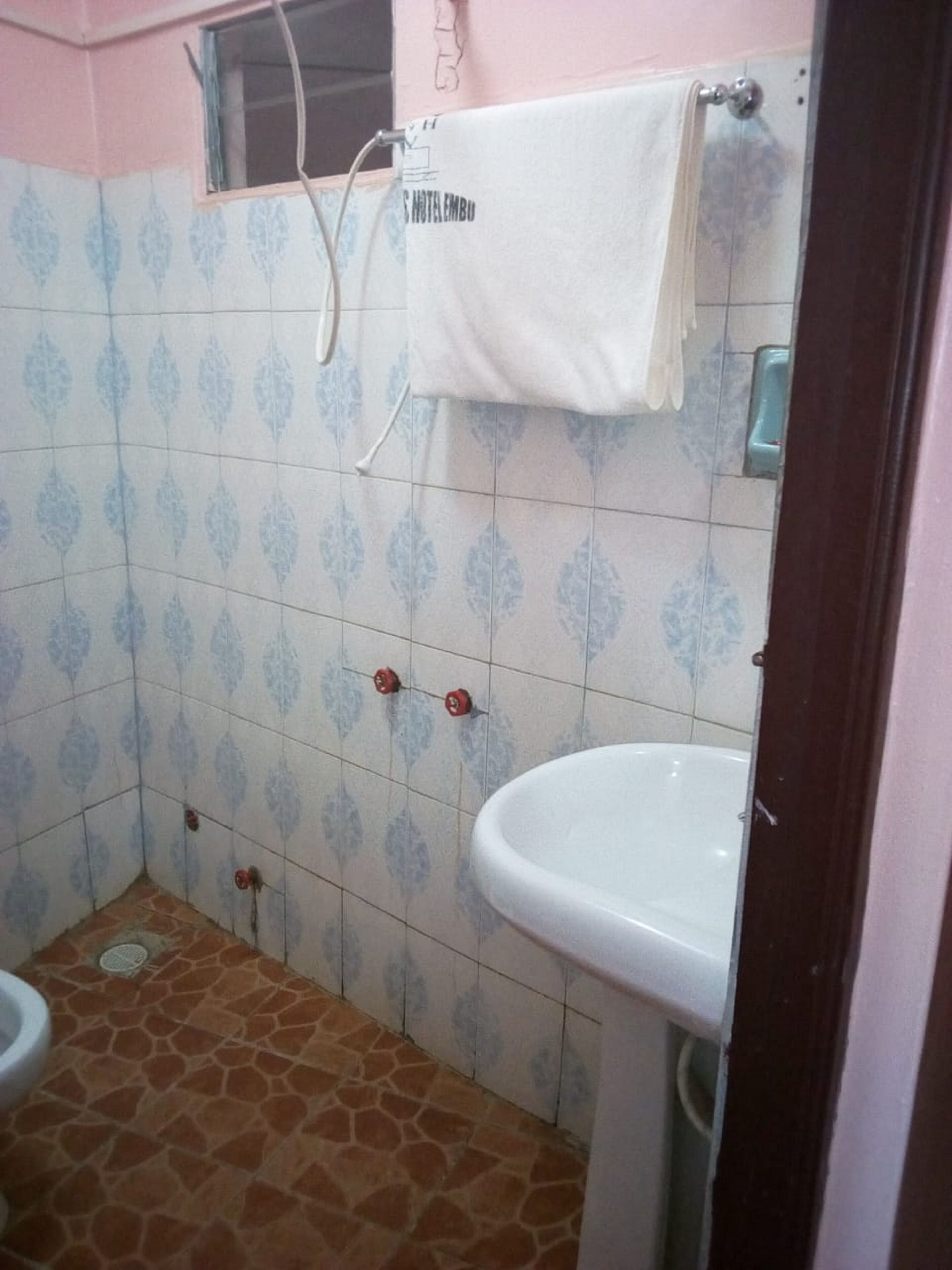 A bathroom with patterned tiles, a white sink, and a towel hanging on a rack.