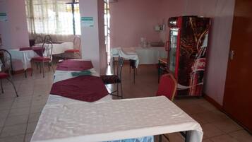 Habitación de hotel con cama, mesa de comedor, sillas, refrigerador y ventana con cortinas.
