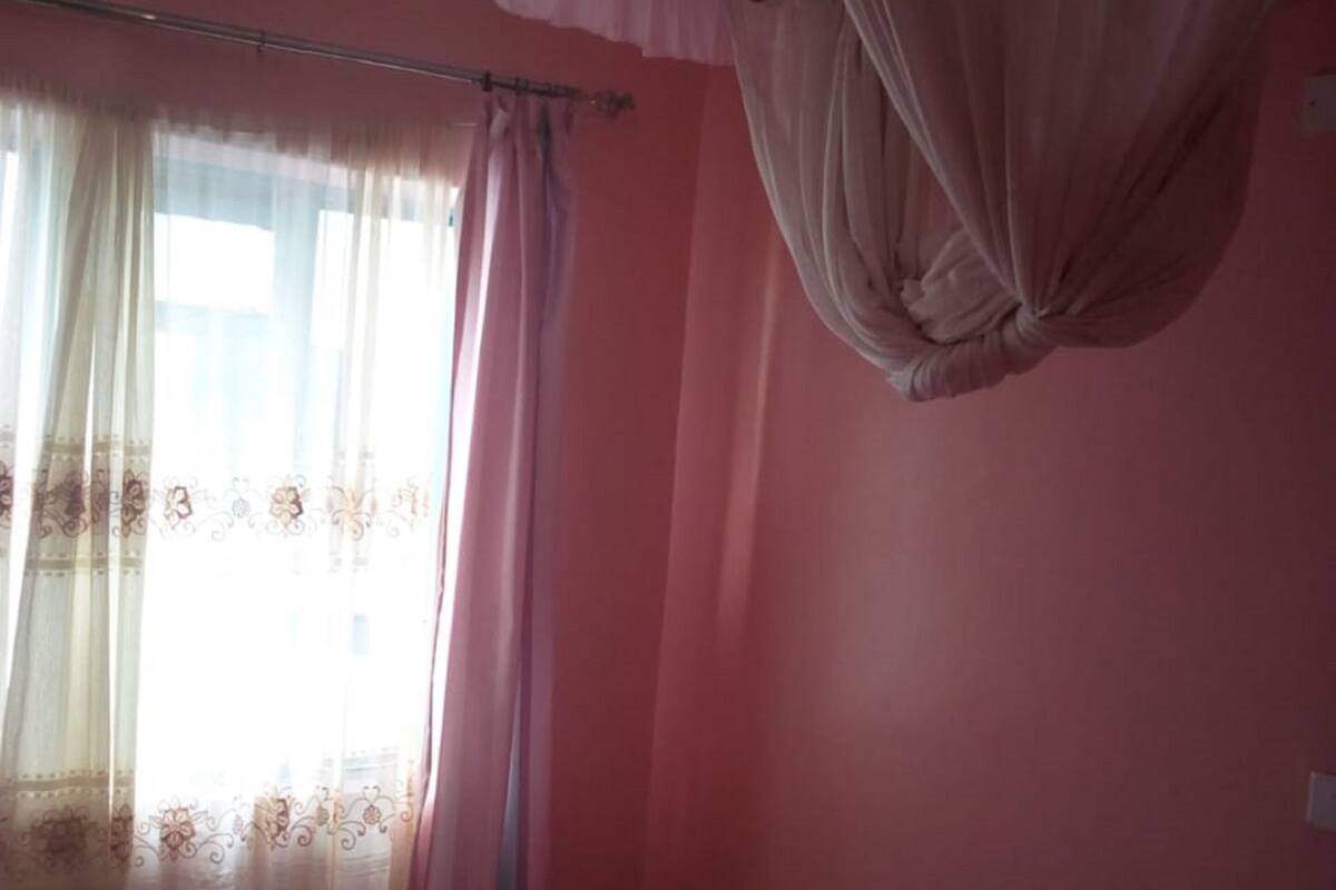 Ein Schlafzimmer mit Bett, einem Fenster mit Vorhängen und einem Deckenventilator.