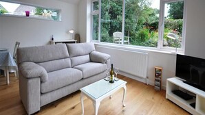 Un soggiorno moderno con un divano grigio, un tavolino in vetro e una TV su un mobile bianco.