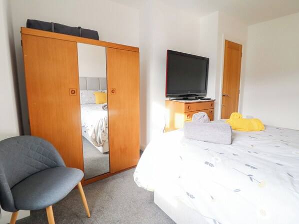 A hotel room with a bed, a TV, a wardrobe, and a chair. - Arnant (Dolgellau)