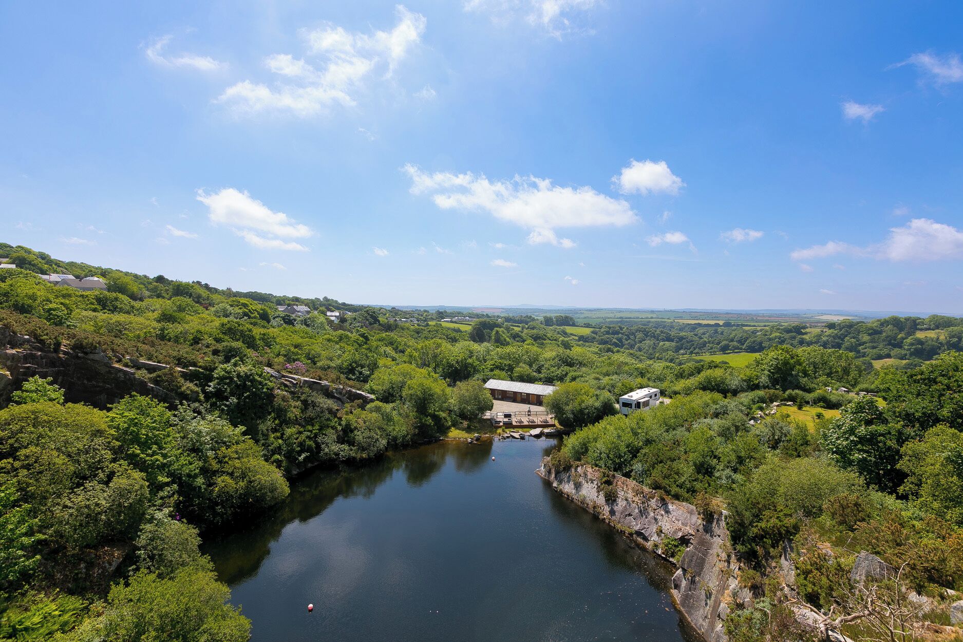 A river with a bridge, surrounded by lush greenery and a clear sky.