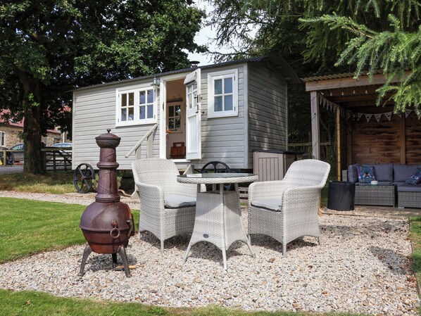 A rustic cabin with a dining area featuring wicker furniture and a vintage stove.