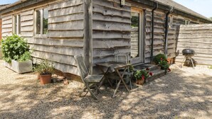 A rustic wooden cabin with a gravel driveway, a wooden bench, and potted plants. - Pond View (Fordingbridge)