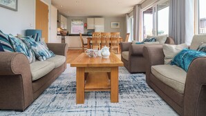 Un salon moderne avec deux canapés, une table basse en bois et un coin repas comprenant des chaises et une table.