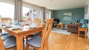 Un coin repas avec une table en bois dressée pour quatre personnes, un canapé et un téléviseur dans un salon aux murs de couleur turquoise.