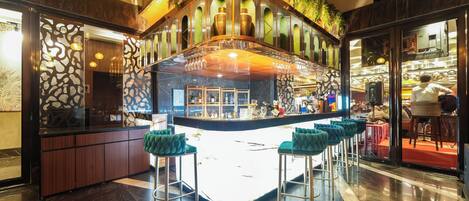 A bar area with a curved counter, bar stools, and a view of the street outside.
