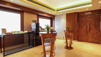 A modern bar area with a coffee machine, a decorative plant, and a patterned wall.