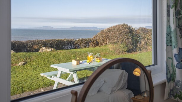 Una habitación con un amplio ventanal que da a una zona verde y al mar.