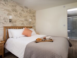 A neatly made bed with a wooden headboard, a grey quilt, and a tray with croissants and coffee cups. - Lambs Lodge (Bamburgh)