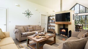 A cozy living room with a sofa, a coffee table, and a fireplace. - Lambs Lodge (Bamburgh)