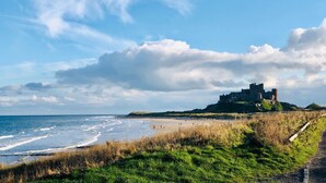 A coastal view with a castle on a hill overlooking the beach. - Lambs Lodge (Bamburgh)