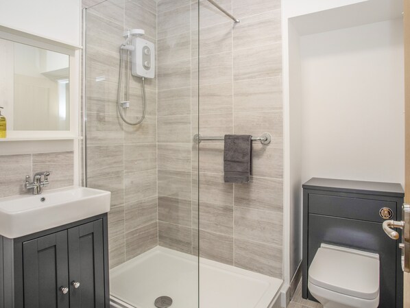 A modern bathroom with a glass shower enclosure, a white sink, and a toilet.