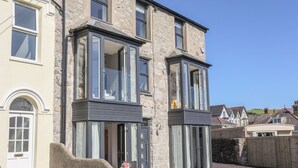 A two-story stone building with large windows and a balcony. - Cambrian House (Criccieth)