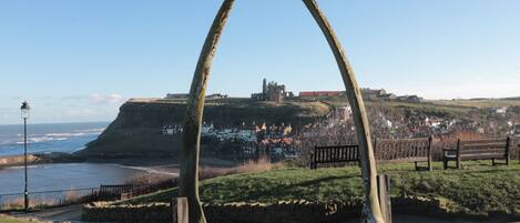 A coastal town with a prominent arch structure, a historic building, and a view of the sea.
