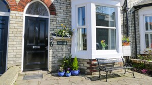 Un bâtiment avec une porte noire, une enseigne indiquant « Sailors Lodge », et une baie vitrée ornée de plantes en pot.